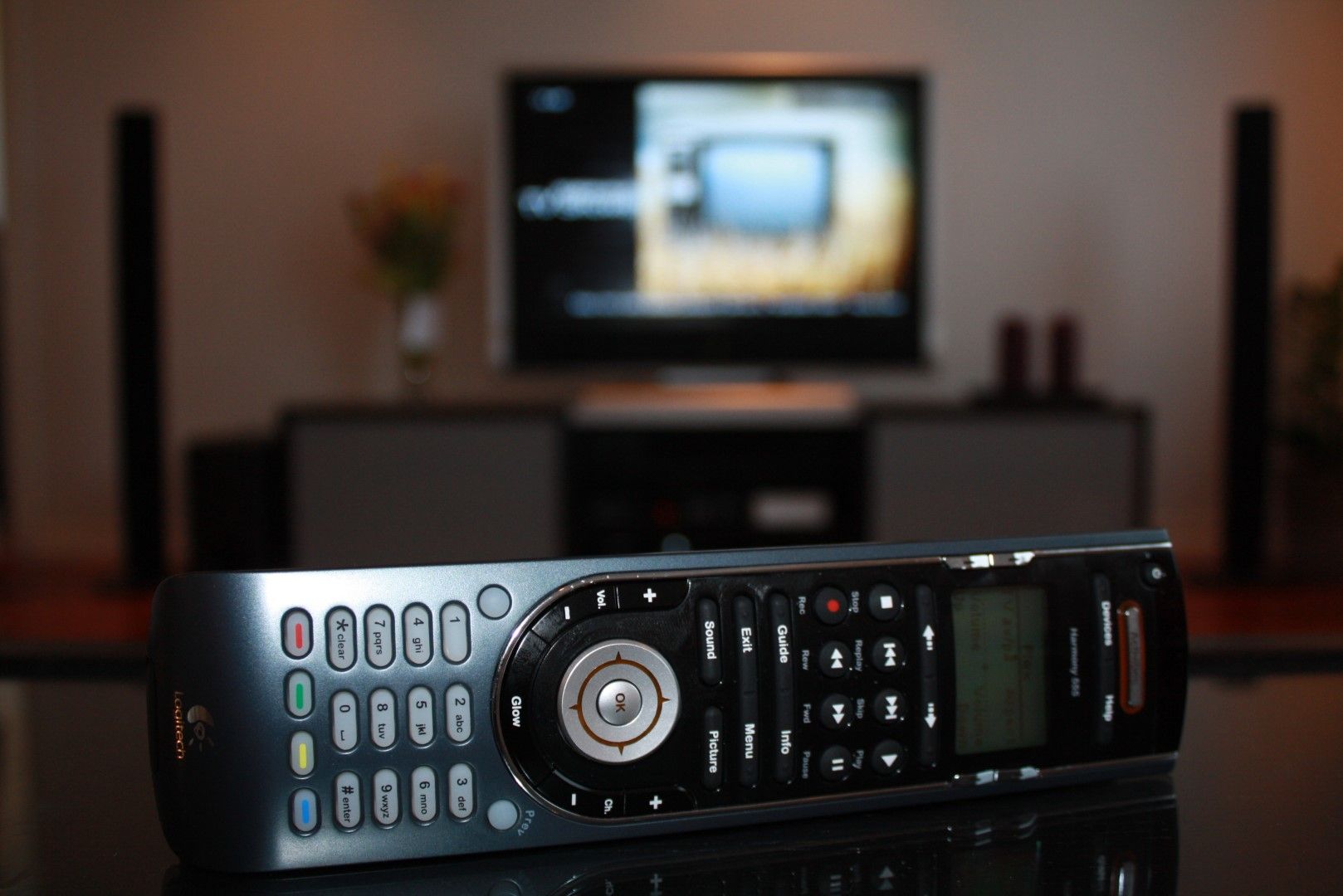 A Logitech Harmony 555 remote with an LCD screen, a D-pad, and a number of TV and media keys.