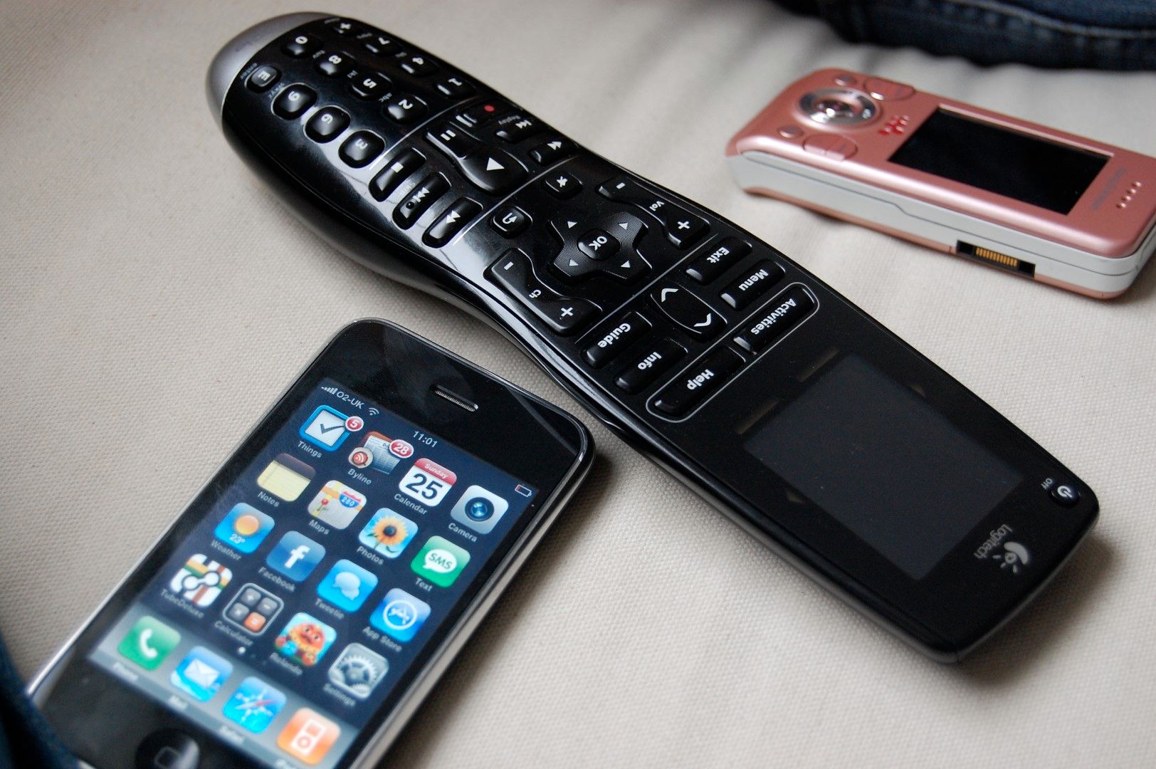 The Logitech Harmony One remote, alongside with a Sony Ericcsson slider phone and one of initial iPhone models.